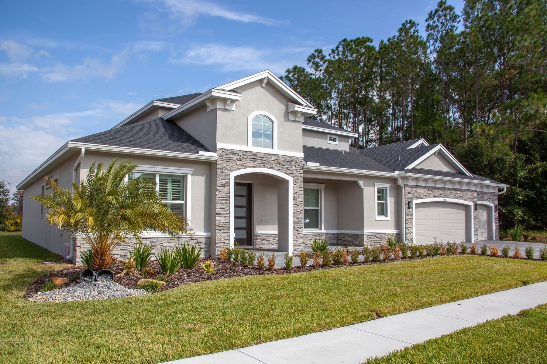 Well-kept single-family home with a lawn, palm, and garage. Stock photograph; not a SpenceCo customer property.